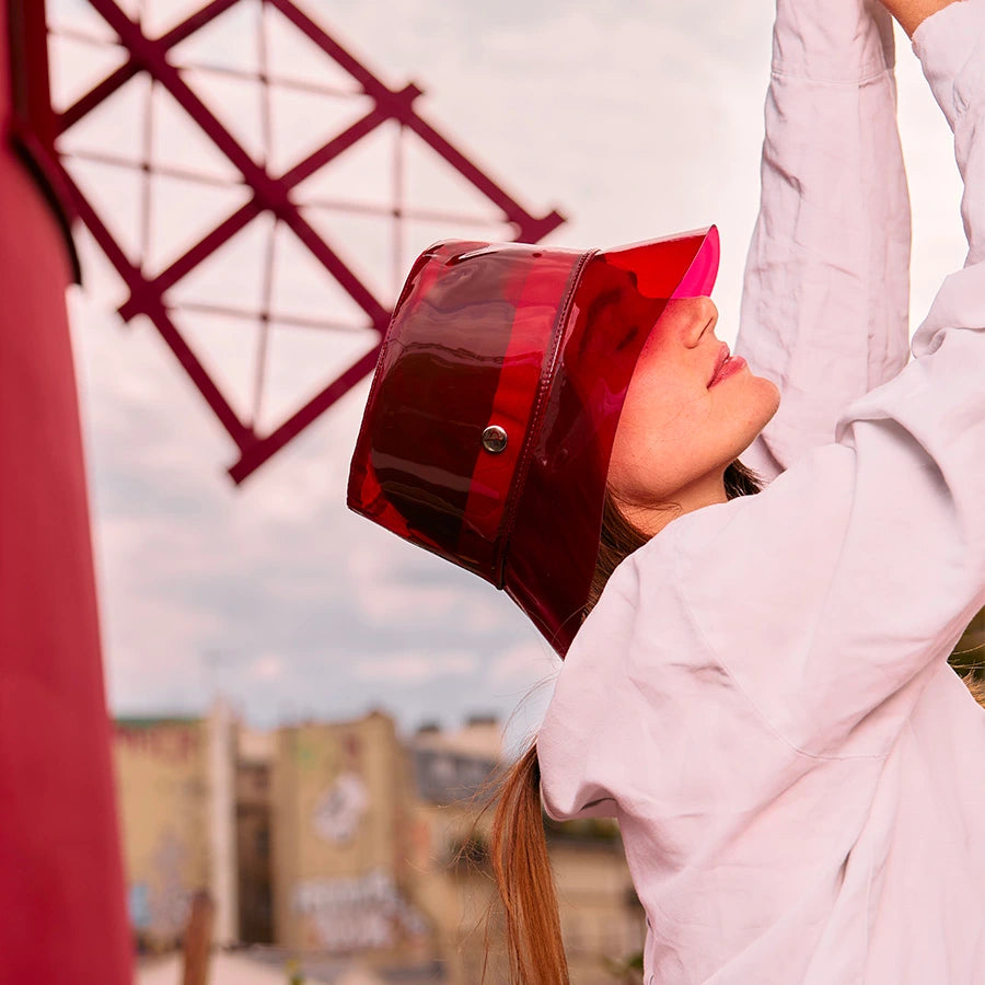 Femme de côté portant le bob Moulin rouge x Lastelier en vinyle rouge transparent sur la tête