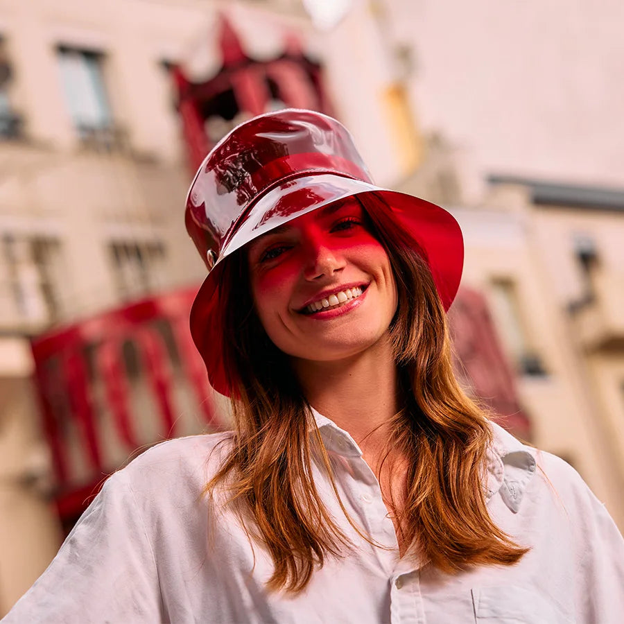 Femme souriante portant le bob vinyle rouge transparent Moulin rouge x Lastelier