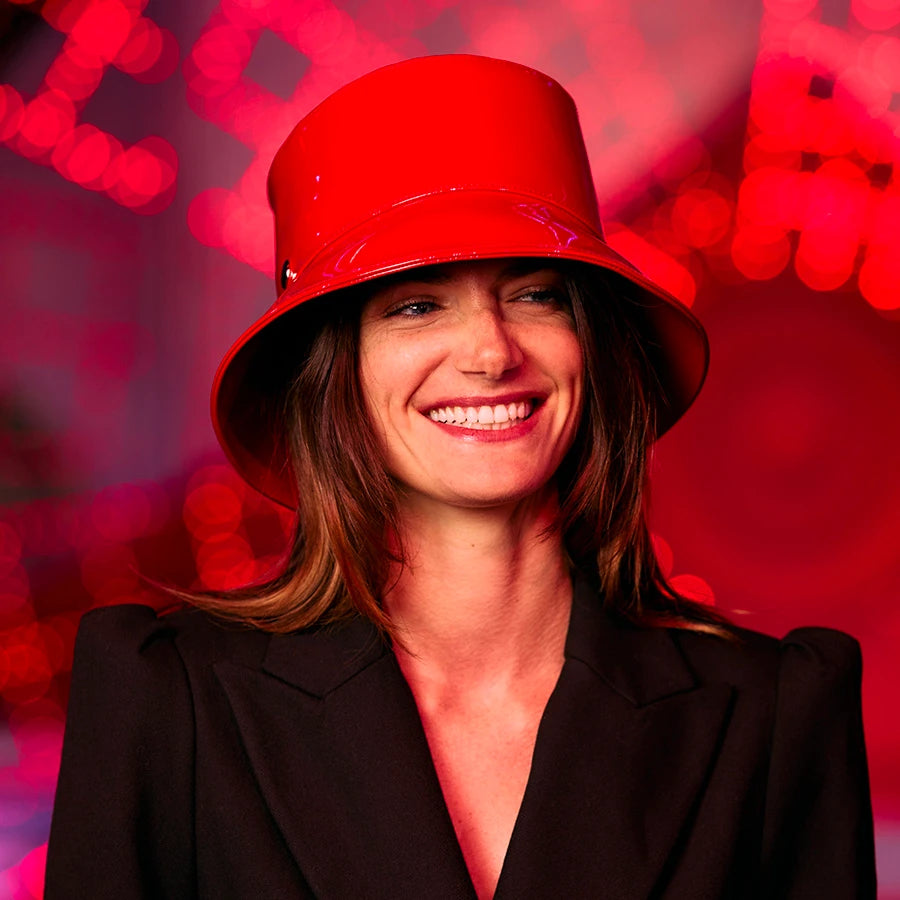 Femme en costume noir souriante portant le bob vinyle rouge Moulin rouge x Lastelier